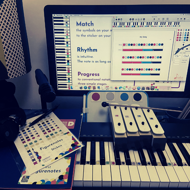 A lot of Figurenotes resources gathered around a computer and a keyboard with figurenotes stickers