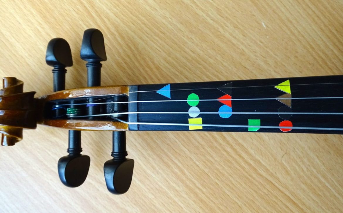 The fingerboard of a violin with Figurenotes stickers on the natural notes.