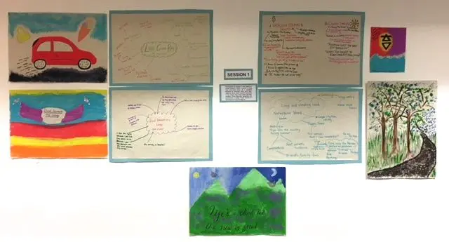 Posters and images, including a green mountain landscape, are displayed on a white wall
