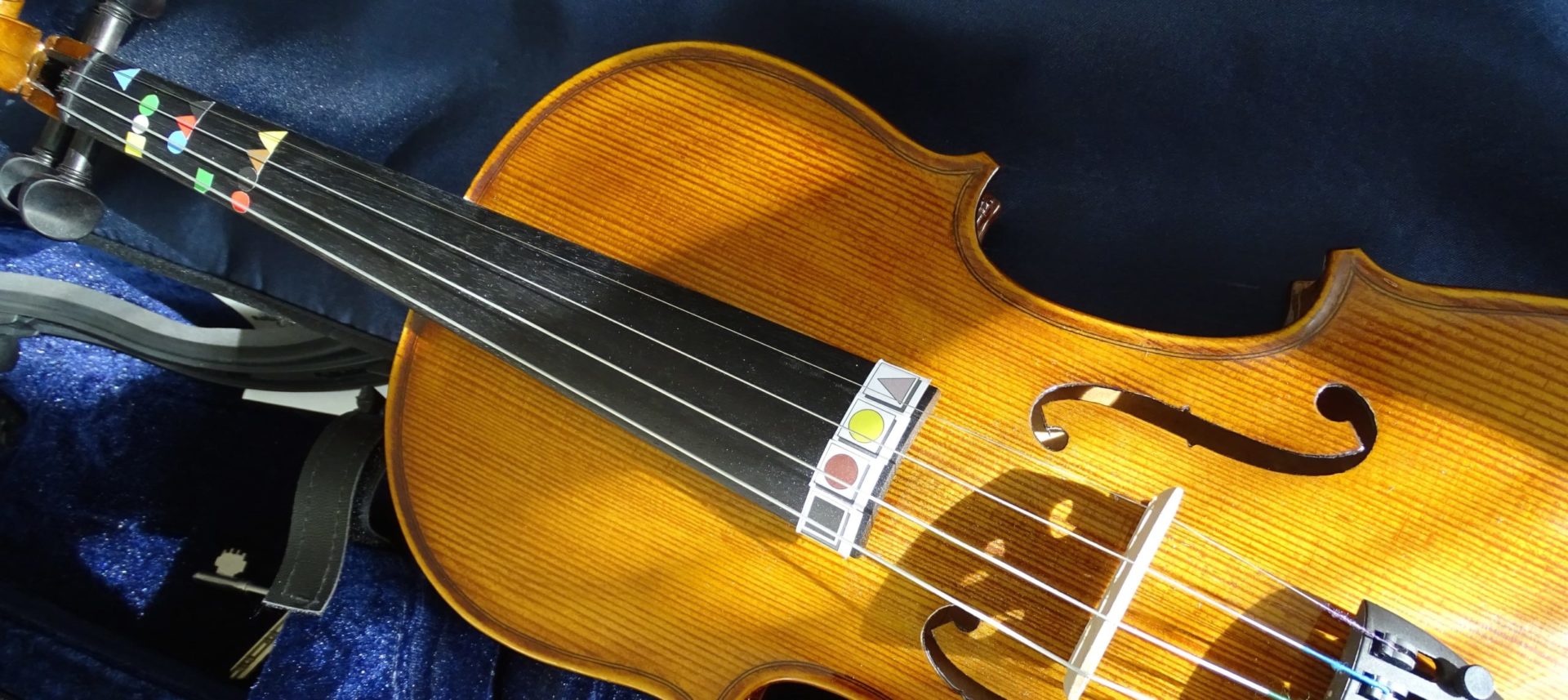 Image representing the Instrument guides section of the website. Violin set down facing upwards with Figurenotes stickers on both the neck and at the end of the bridge.