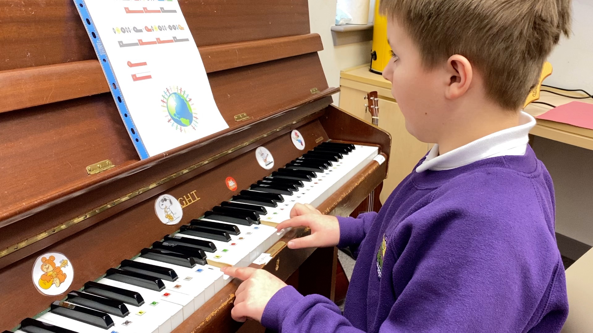 Young boy in purple jumper playing piano using Figurenotes.