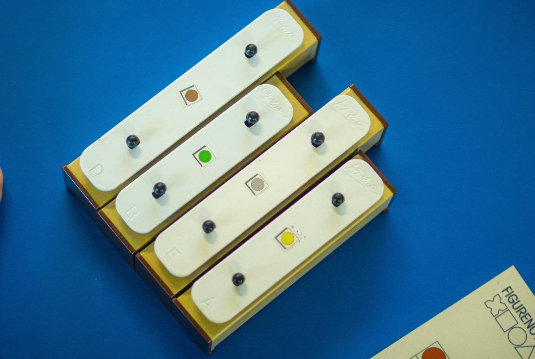 4 chime bars with small coloured shapes stuck to them. The background is blue. There is a Figurenotes score just visible at the bottom edge.