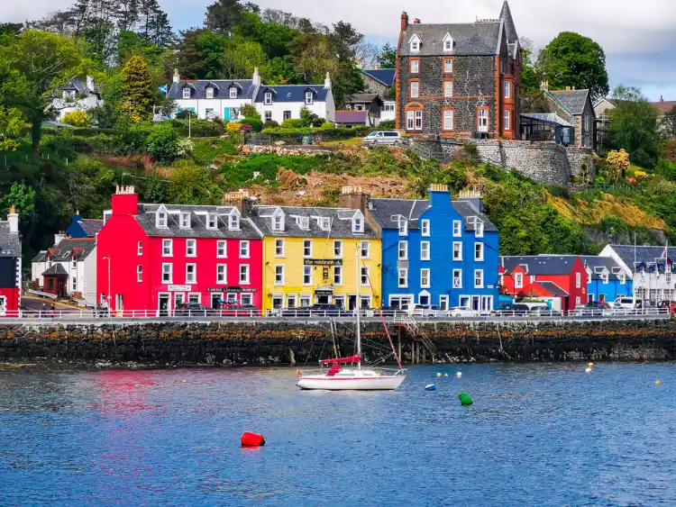An image of Tobermory harbour edited to include Figurenotes colours. Houses are red, yellow and blue, with a boat bobbing in the harbour in front of them.